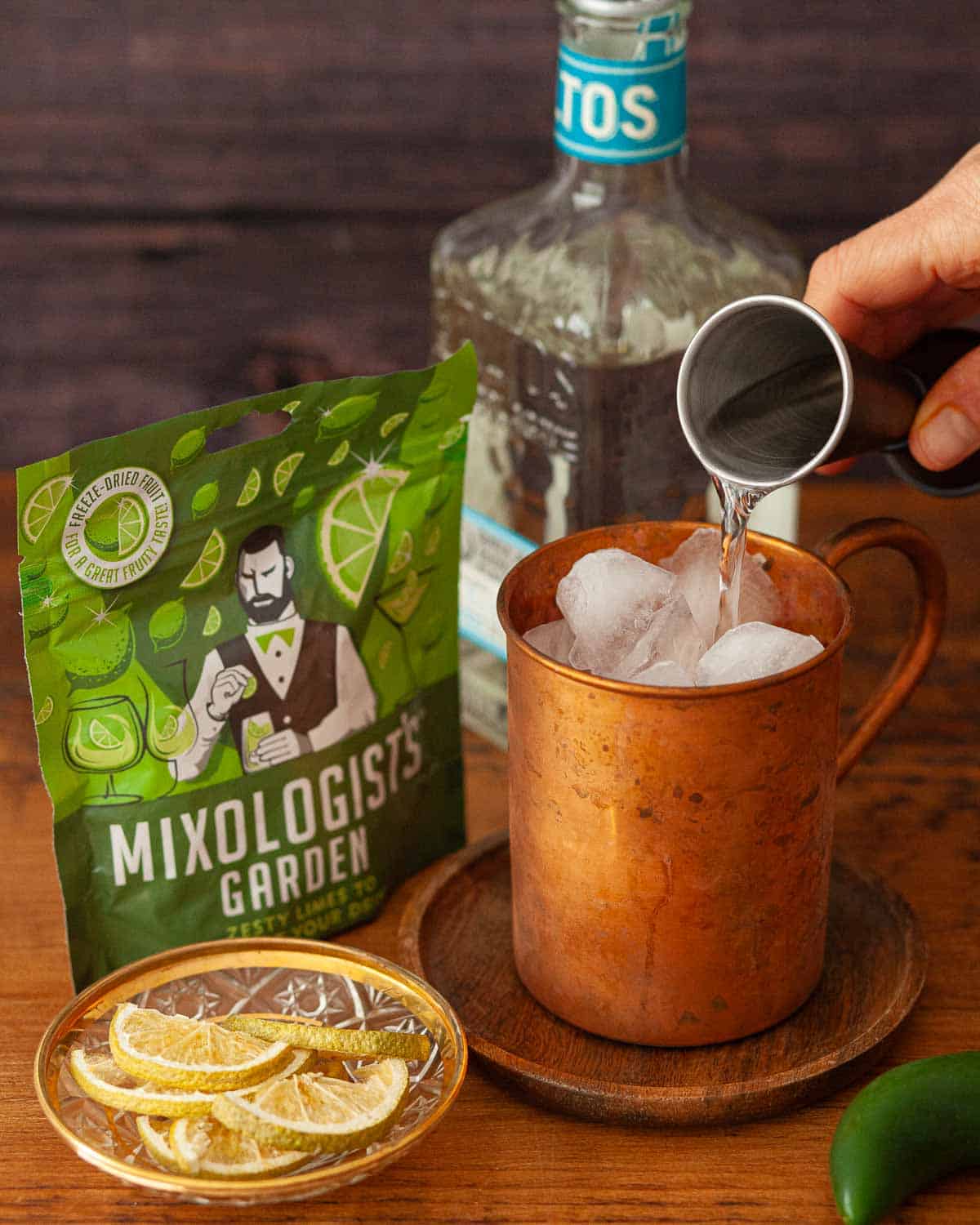 Tequila being poured over ice in a copper mug.