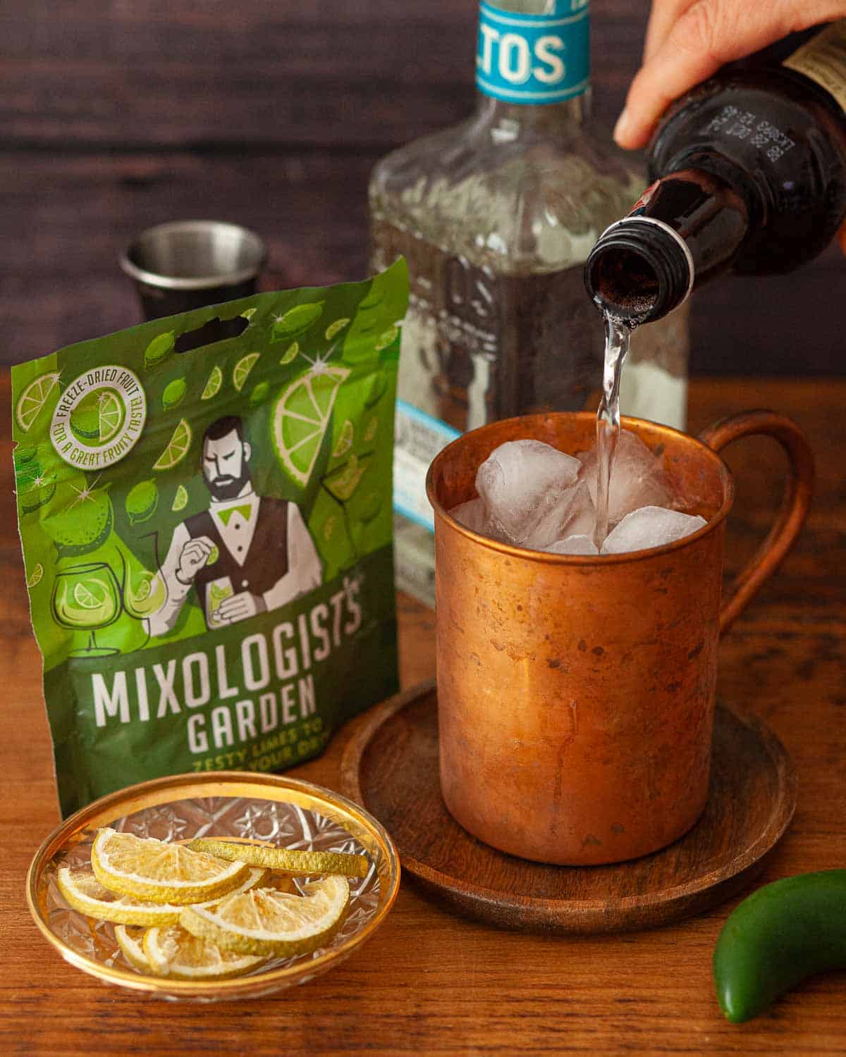 Ginger beer being poured over ice in a copper mug.