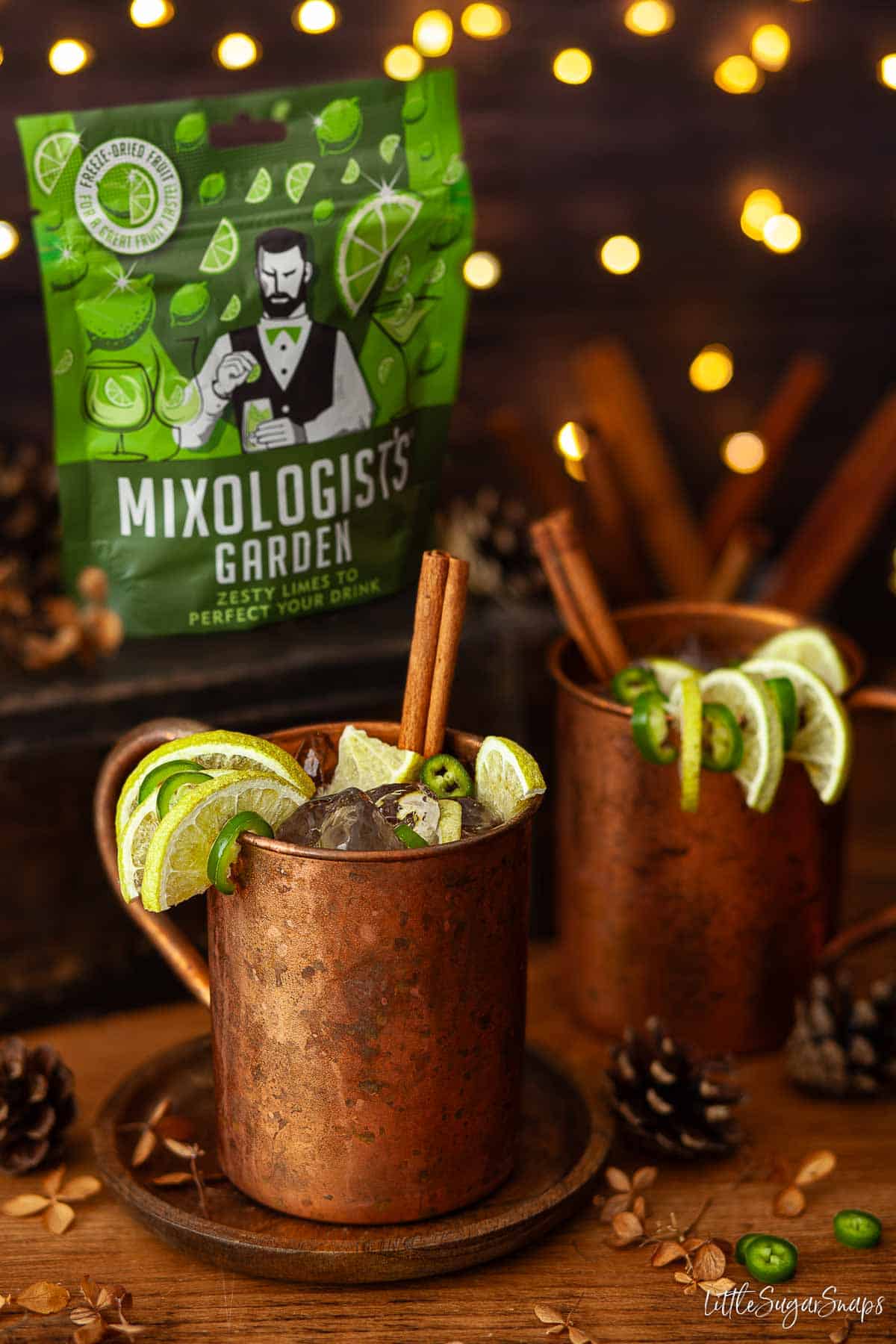 Mexican mule cocktails in copper mugs with lime and chilli garnish plus a packet of lime slices.