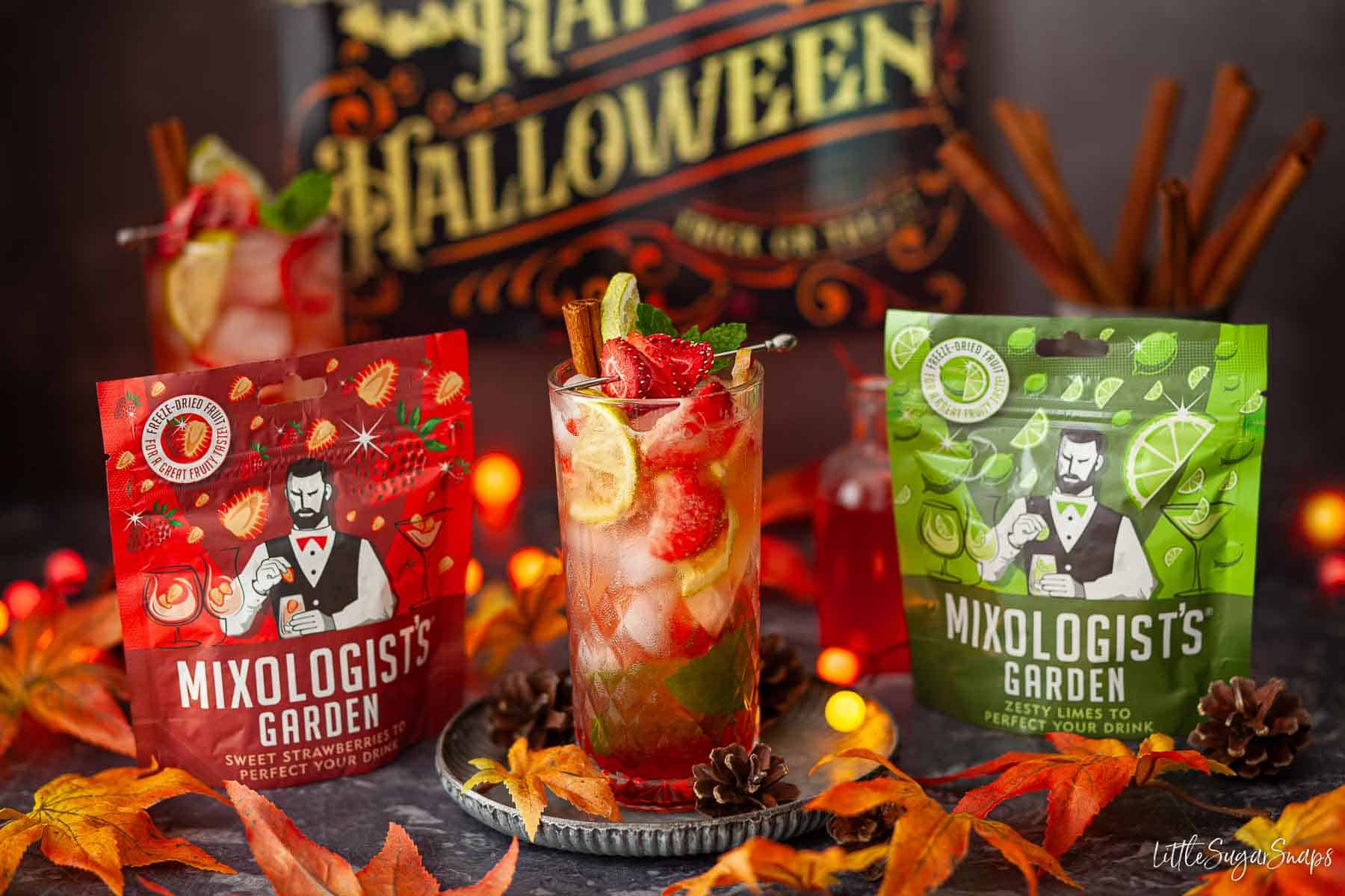 Red mojito cocktails with a bottle of strawberry cocktail syrup and packs of strawberry & lime slices.