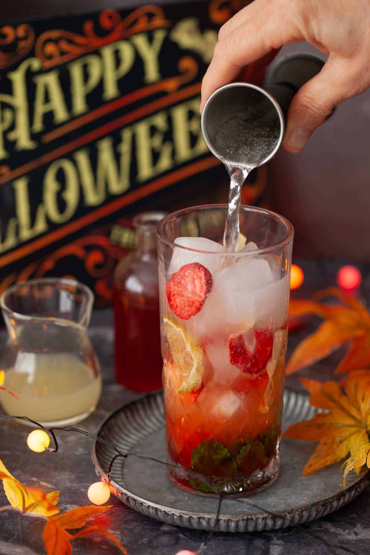 A person pouring soda water into a cocktail.