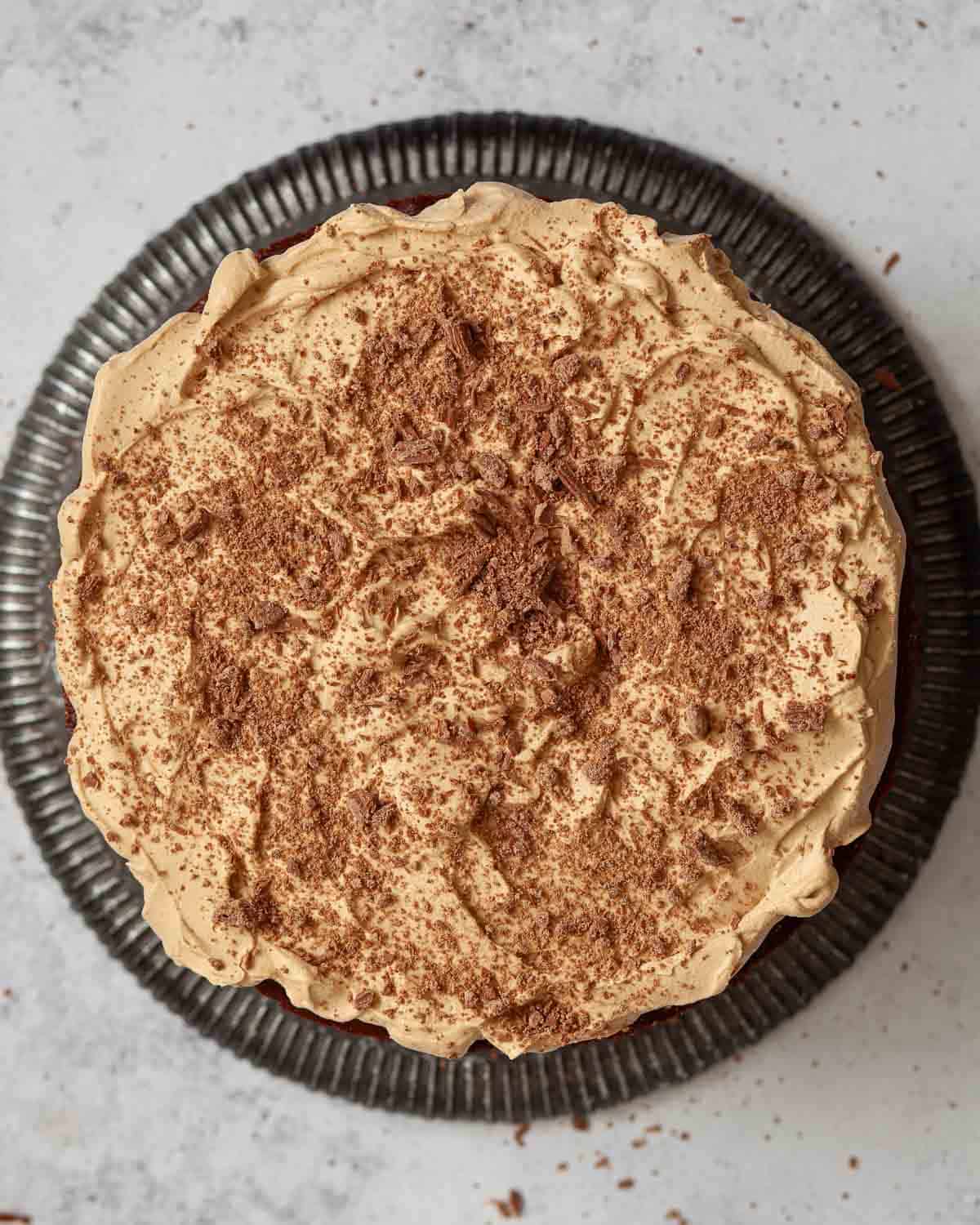Top view of a coffee and chocolate cake decorated with coffee cream and flaked chocolate.