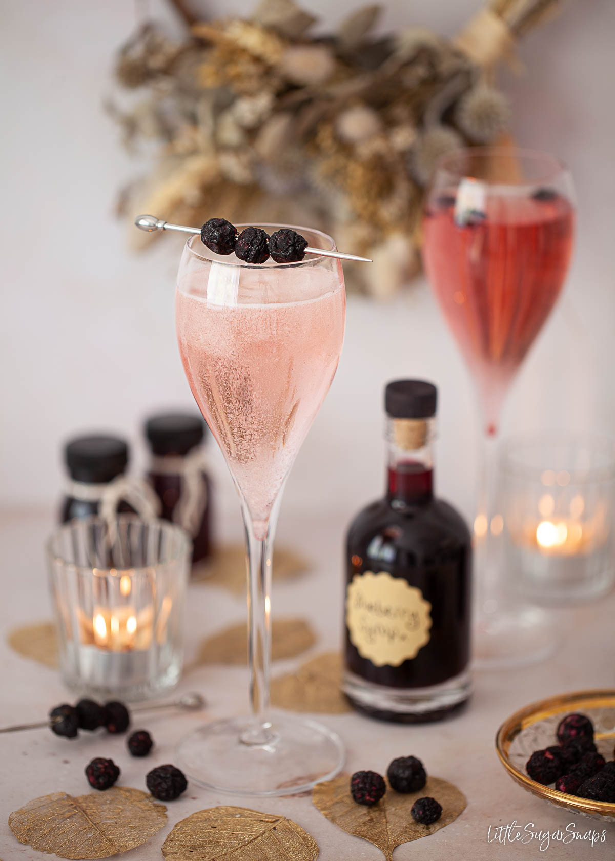 A glass of sparkling wine mixed with blueberry simple syrup and garnished with freeze-dried blueberries.