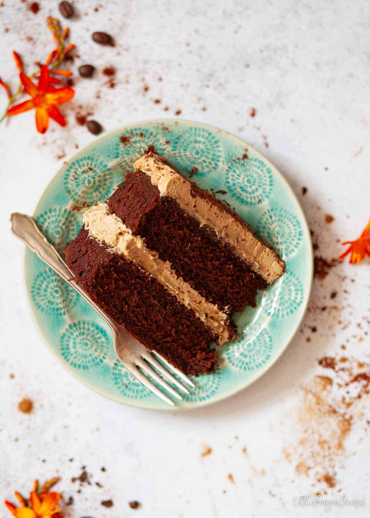 A slice of chocolate and coffee cake on a blue plate with a fork at the side.