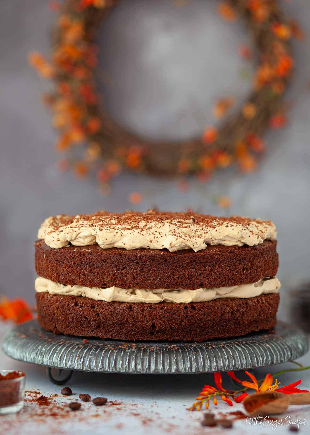 A spiced chocolate coffee cake with coffee whipped cream and Mexican spices in a pot next to it.