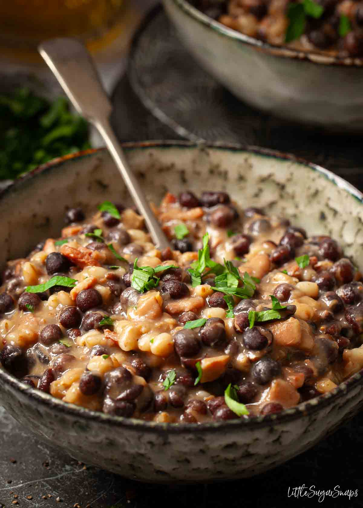 Close-up of grey peys and bacon made from carlin peas in a bowl with parsley garnish.