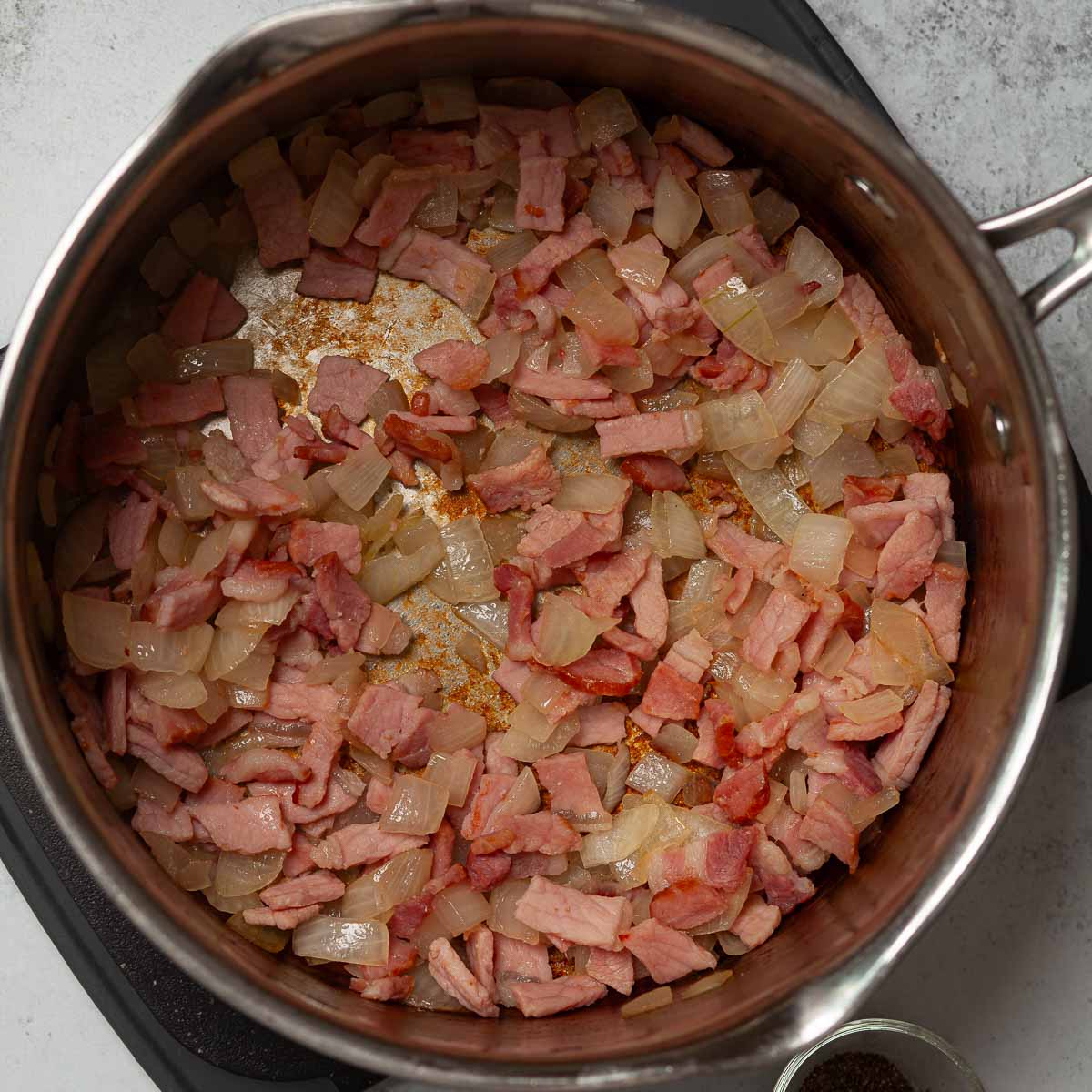 Fried onion and bacon in a pan.