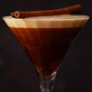 Close-up of a pumpkin spice espresso martini topped with a cinnamon stick.