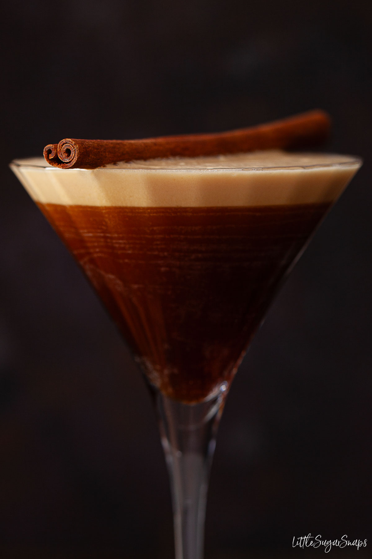 Close-up of a pumpkin spice espresso martini topped with a cinnamon stick.