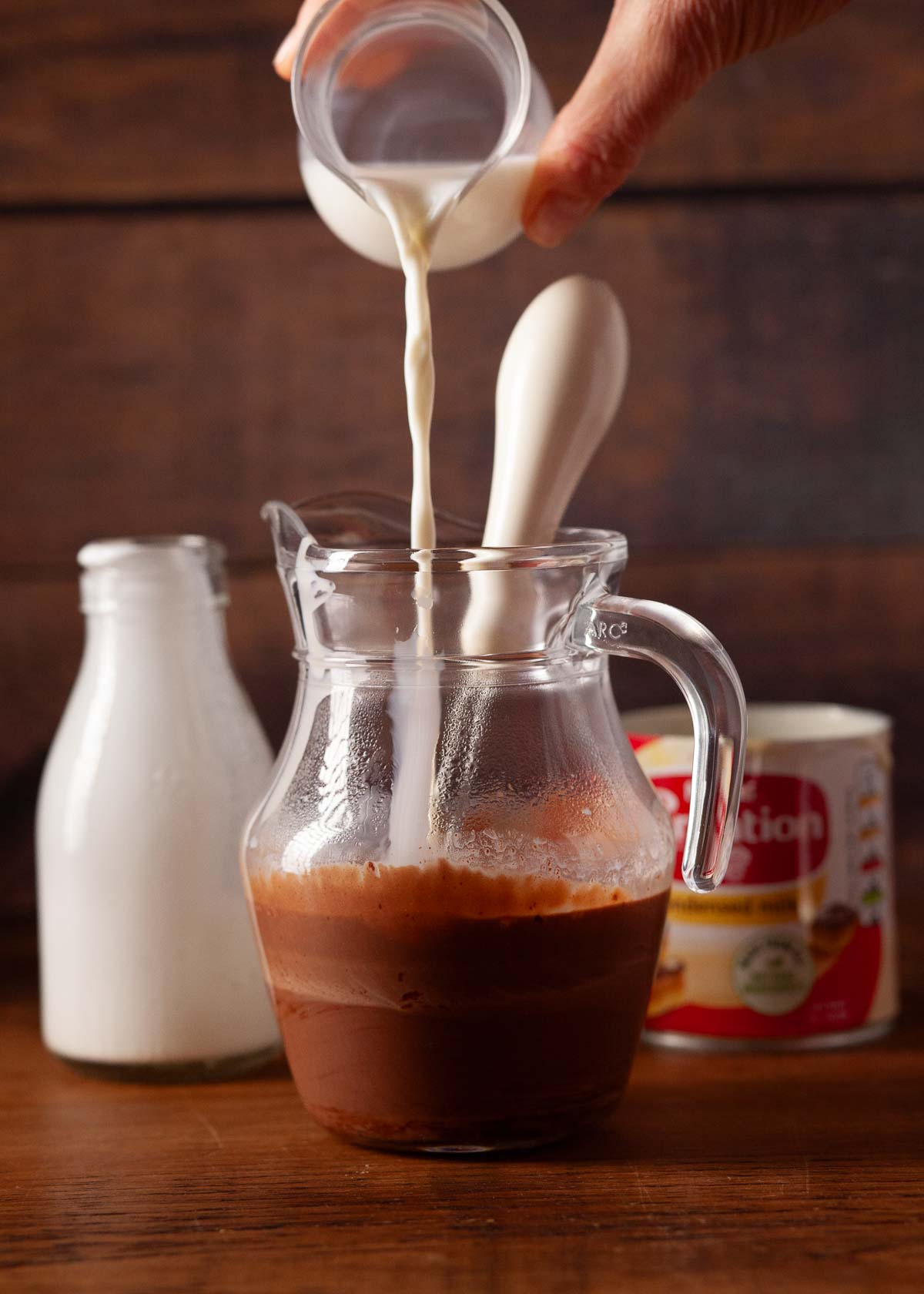 Cream being poured into a jug of melted chocolate and cream.