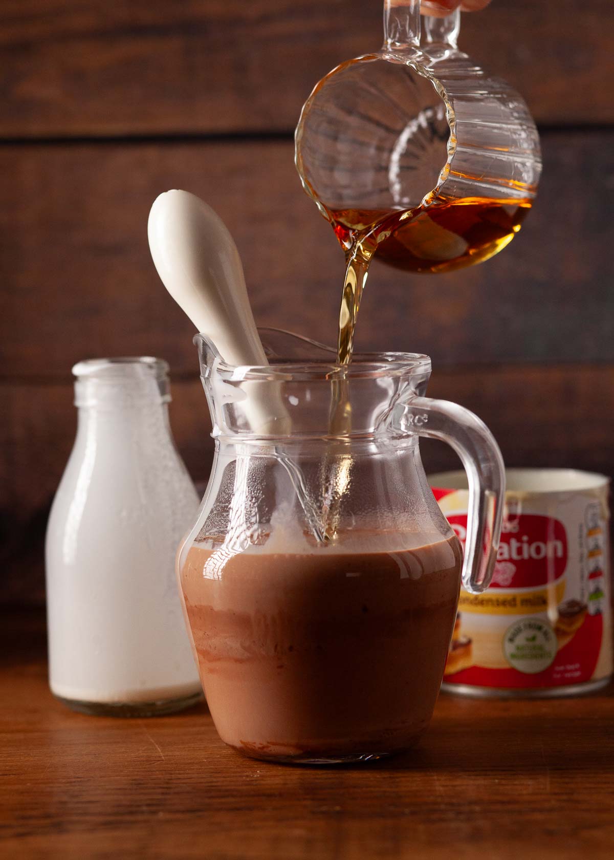 Brandy being poured into a jug with melted chocolate and cream.