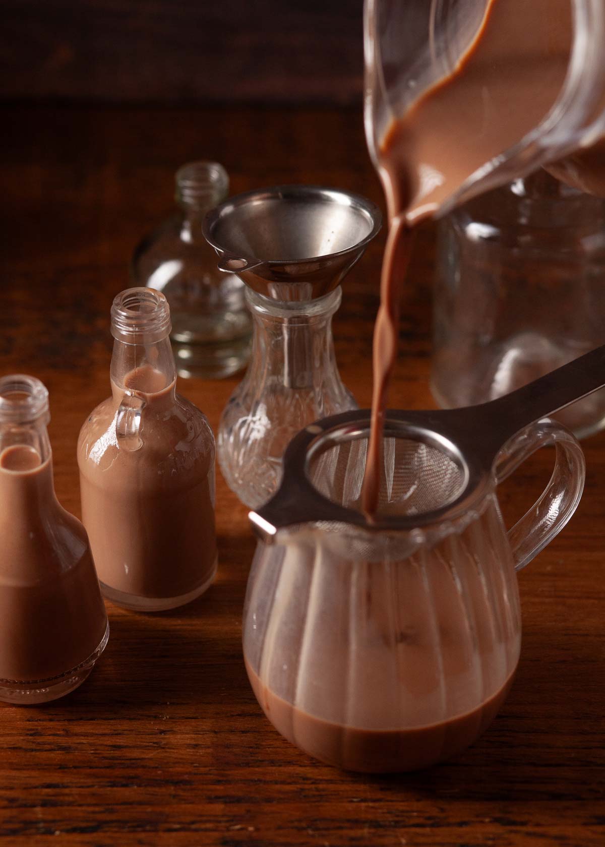 Brandy chocolate liqueur being strained through a small sieve.