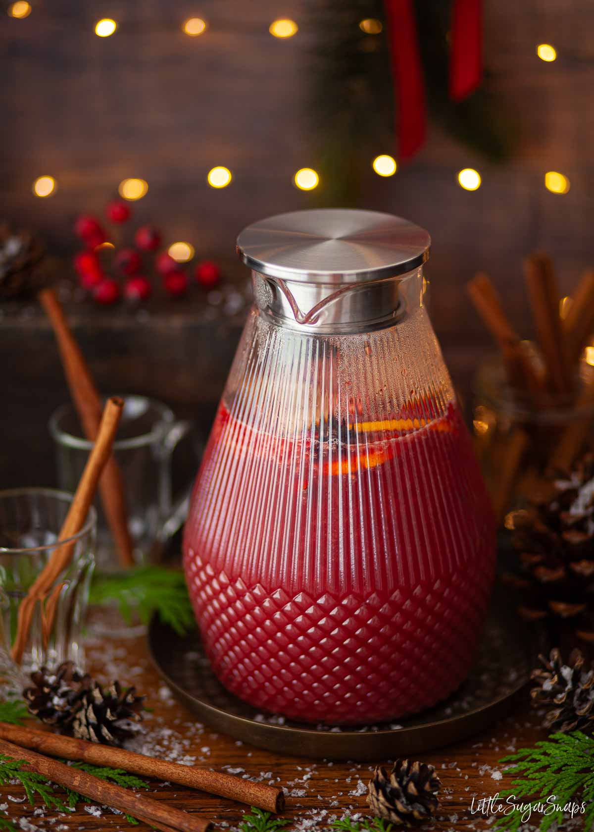 A jug of warm fruit punch mocktail in a festive setting.
