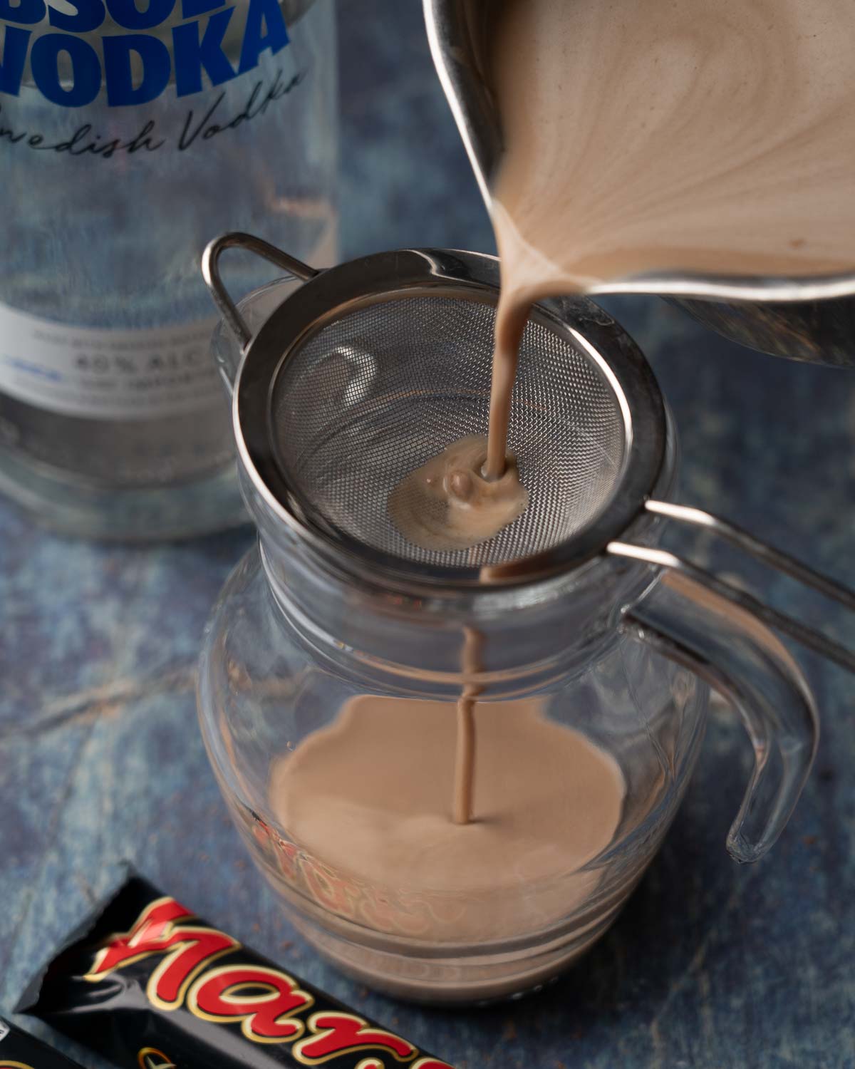 Mars Bar liqueur being passed through a sieve.