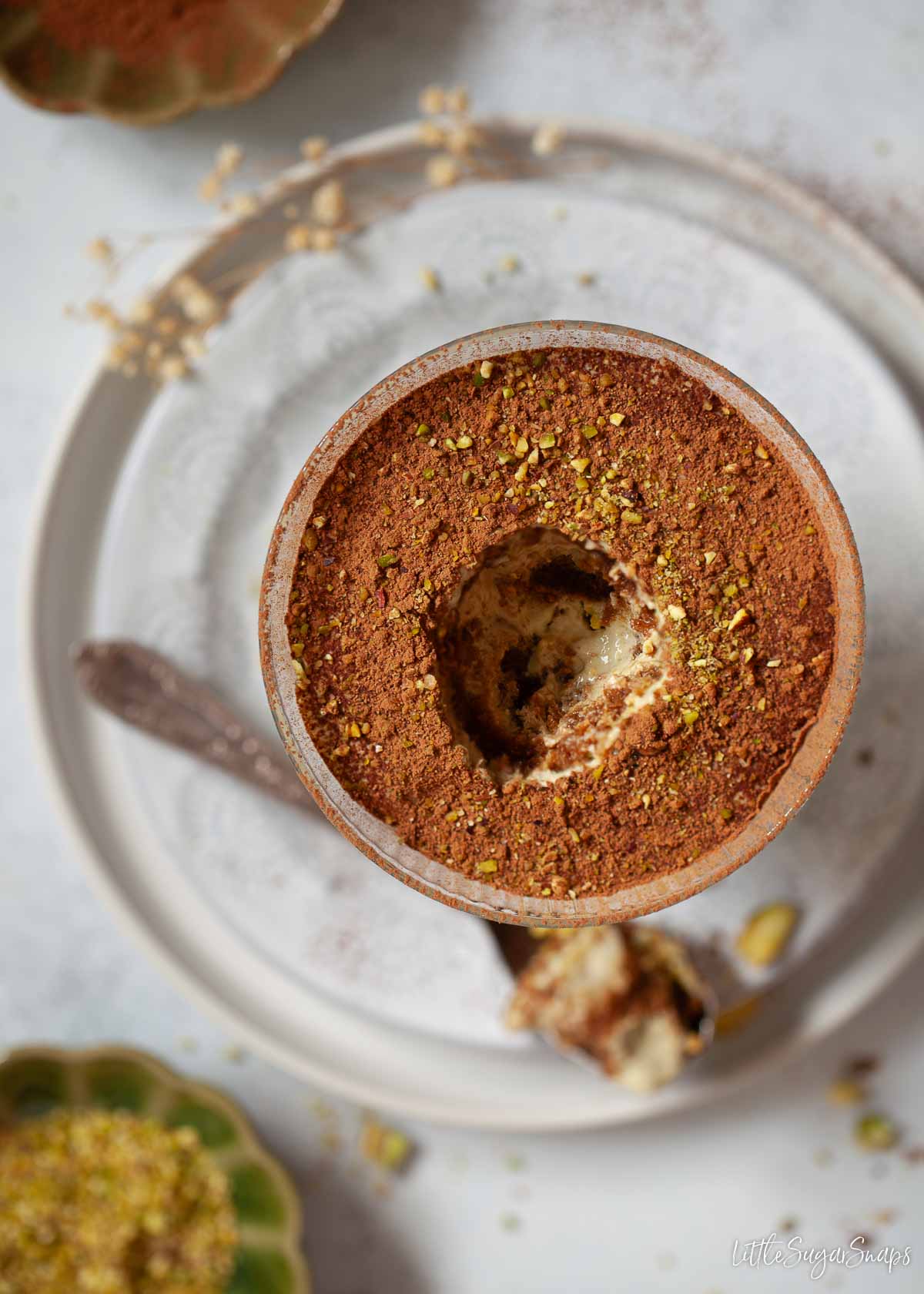 Individual serving of a coffee and pistachio cream dessert with a spoonful removed.