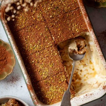 Close up of pistachio tiramisu in a serving dish with two portions removed.
