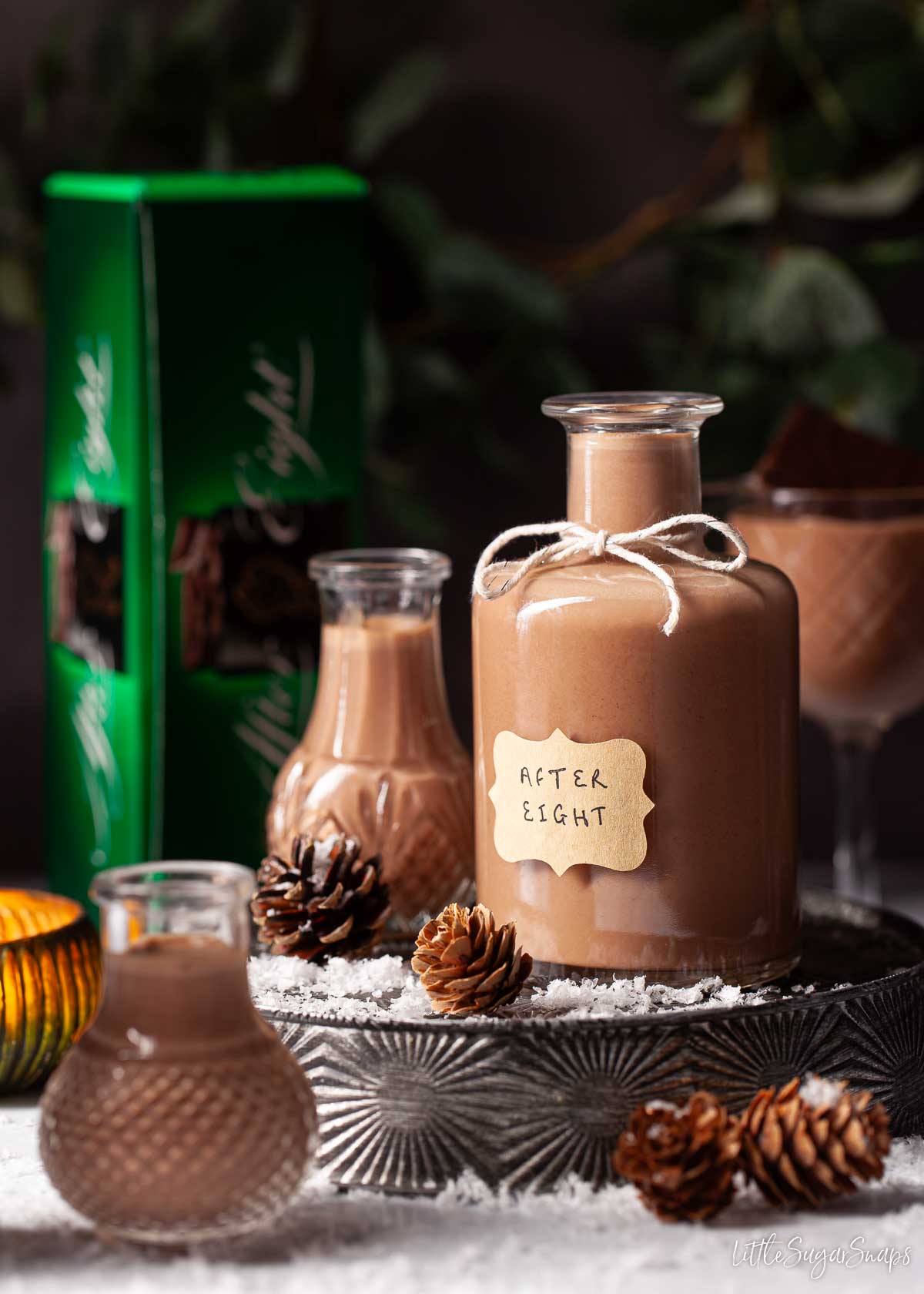 A bottle of homemade After Eight liqueur with a box of mint thin chocolates in the background.