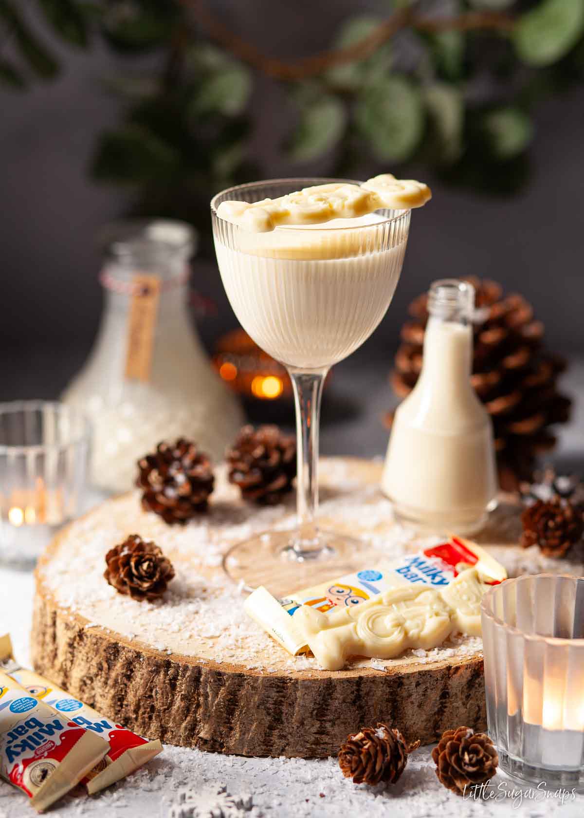 A glass of white chocolate liqueur in a small glass garnished with a Milkybar cowboy.