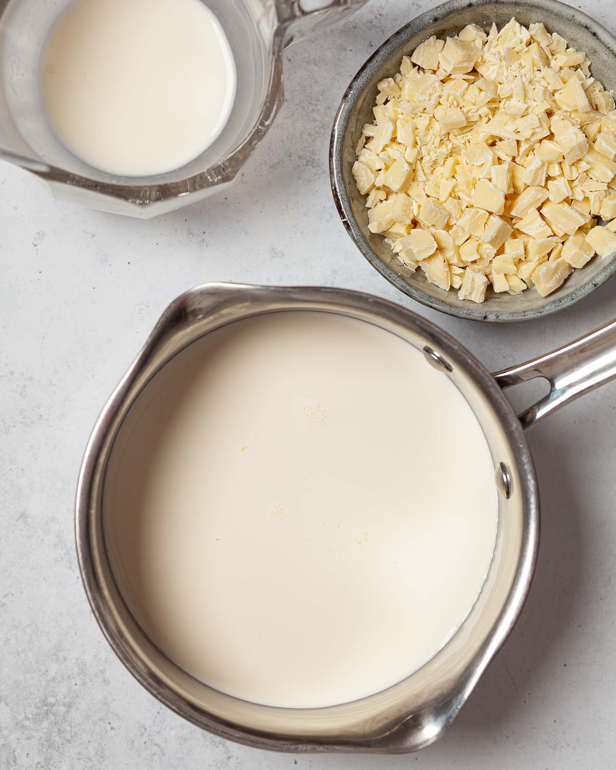Chopped chocolate in a bowl heat to a pan of cream.