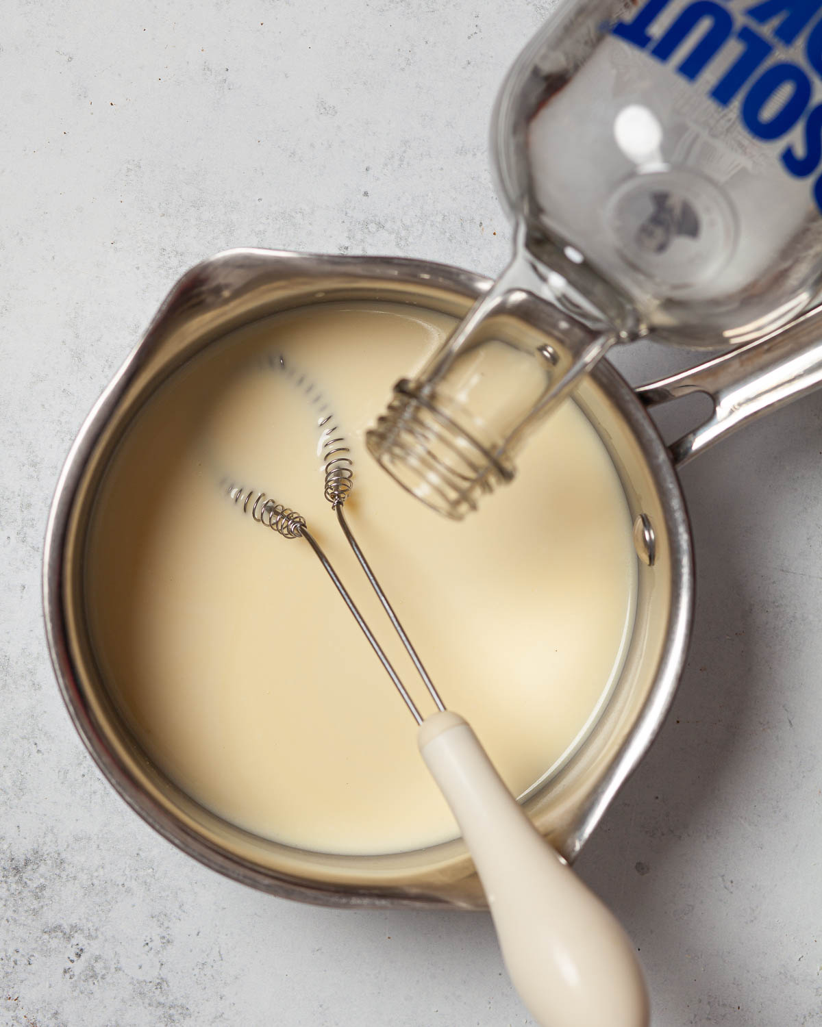 Vodka being poured into a Christmas liqueur made with cream and Milkybar.