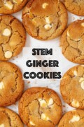Labelled ground ginger on a wooden scoop surrounded by white chocolate ginger cookies.