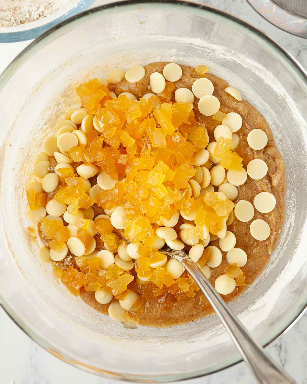 Stem ginger and white chocolate chips in a bowl of cookie dough.