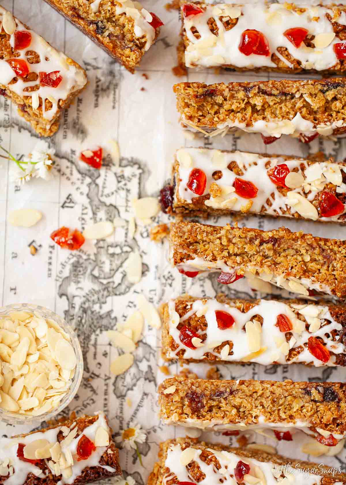 Slices of cherry and almond traybake with slivered almonds in a bowl.