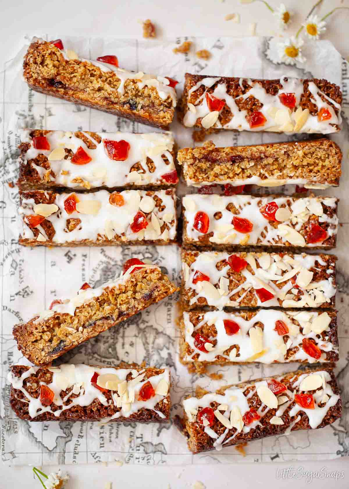 Slices of cherry Bakewell flapjack topped with glacé icing and candied cherries.