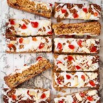 Close-up of slices of cherry Bakewell flapjack with icing, cherries and almonds on the top.