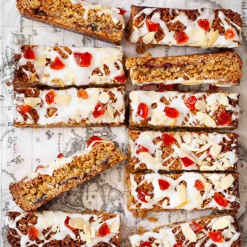 Close-up of slices of cherry Bakewell flapjack with icing, cherries and almonds on the top.