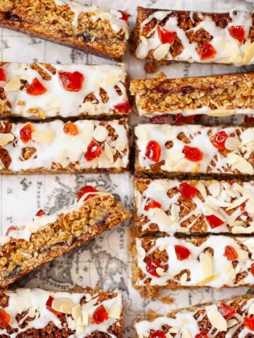Close-up of slices of cherry Bakewell flapjack with icing, cherries and almonds on the top.