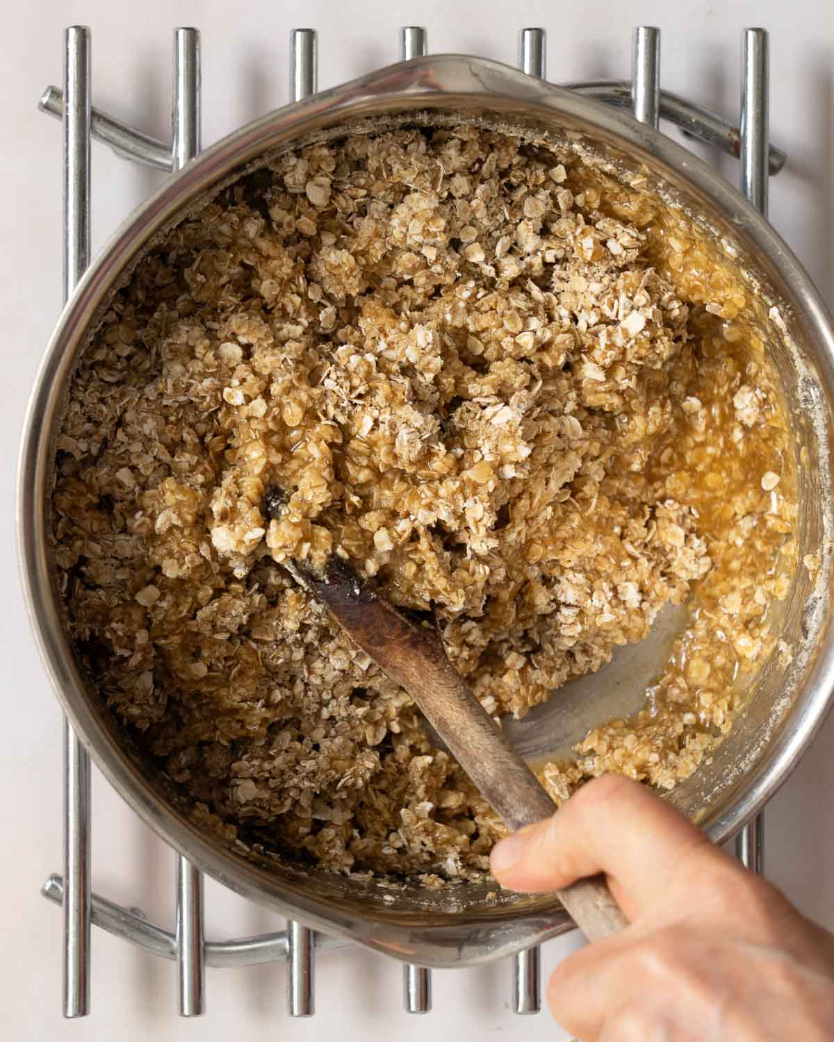 A person stirring oats and ground almonds into flapjack mixture.