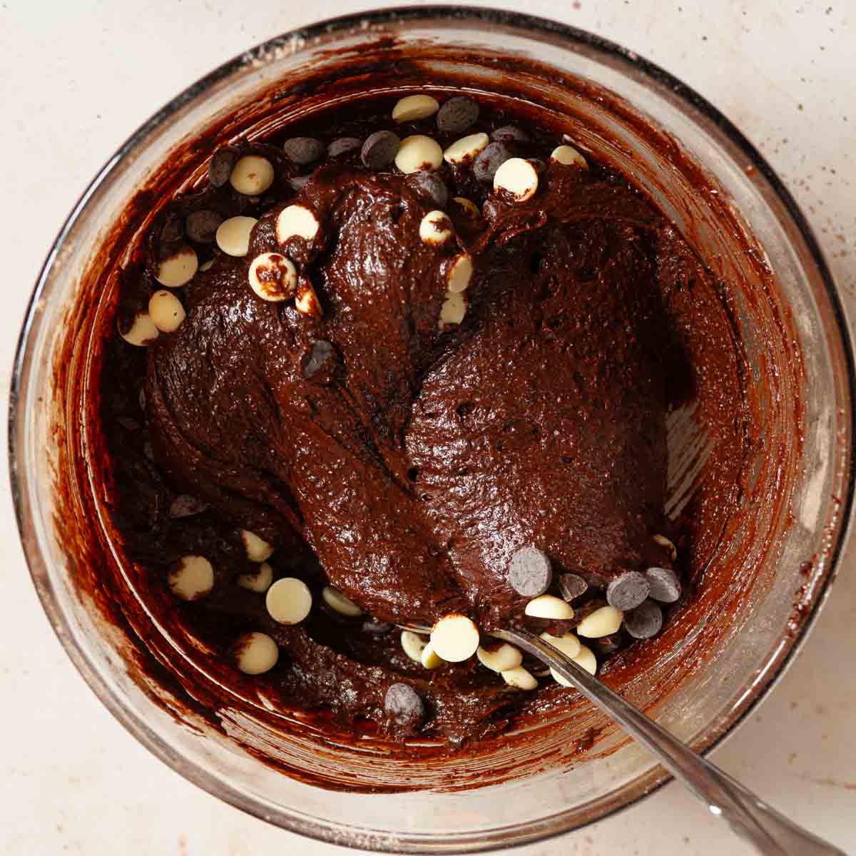 White chocolate and dark chocolate chips being folded into espresso brownie batter.