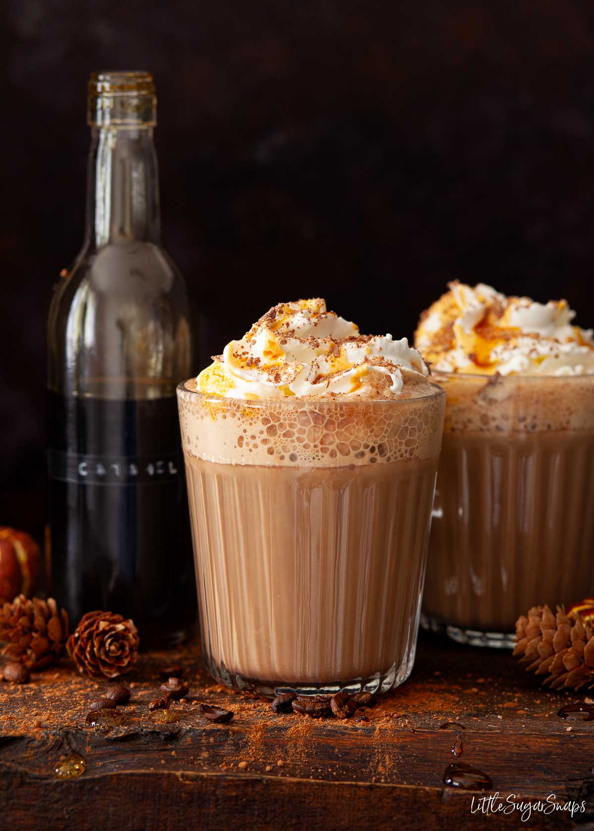 Caramel mocha lattes with whipped cream, chocolate flakes and caramel syrup in a bottle.
