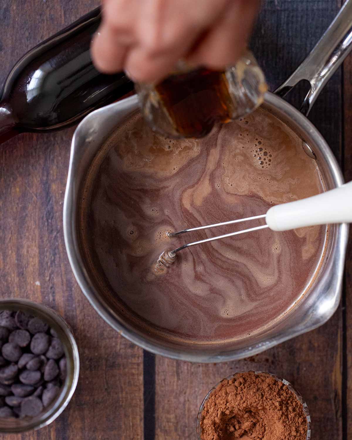 Person pouring espresso into chocolate milk to make a chocolate caramel coffee drink.