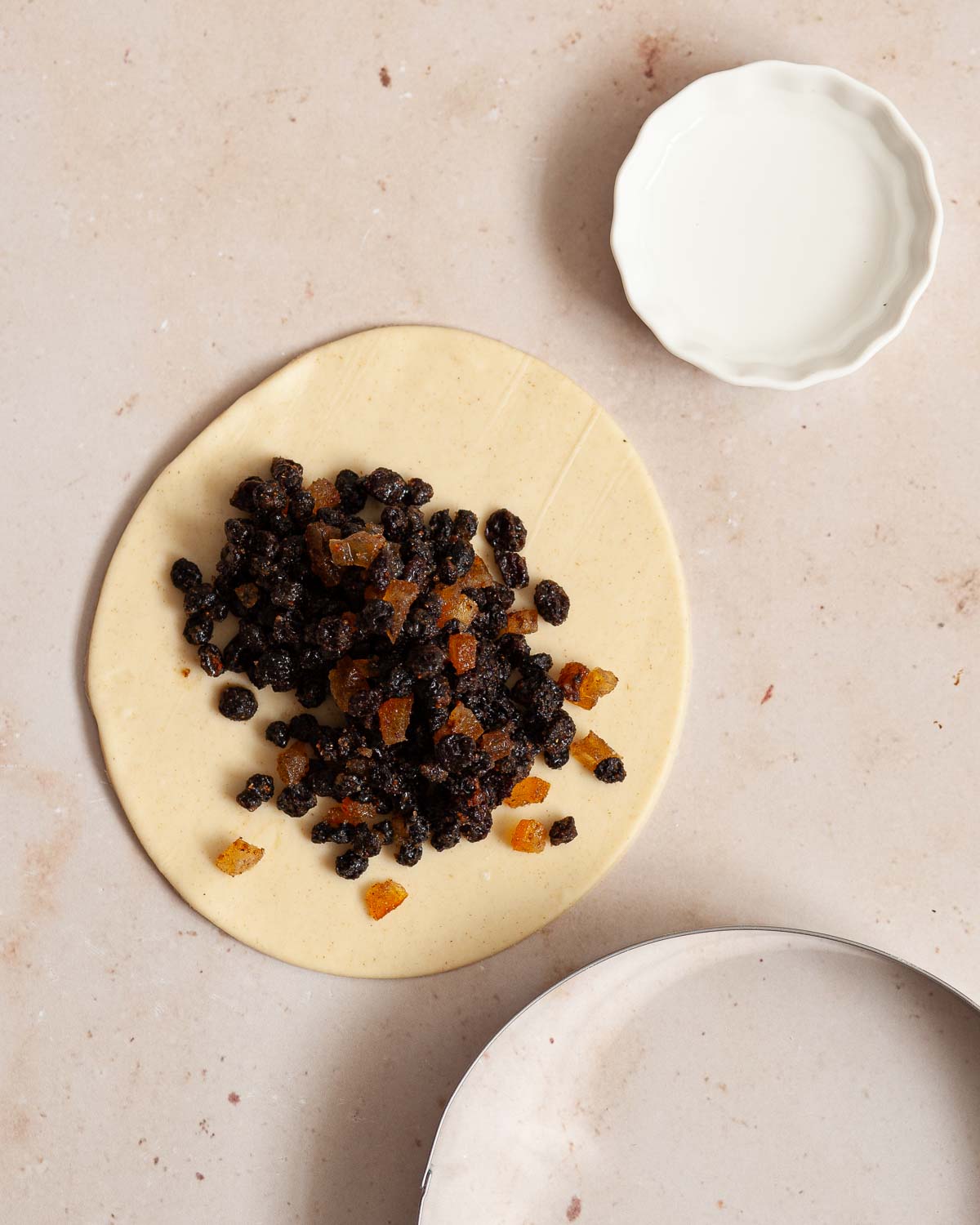 Currants and mixed peel on circles of pastry.