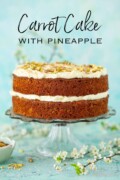 Whole carrot and pineapple cake with coconut on a cake stand with text overlay.