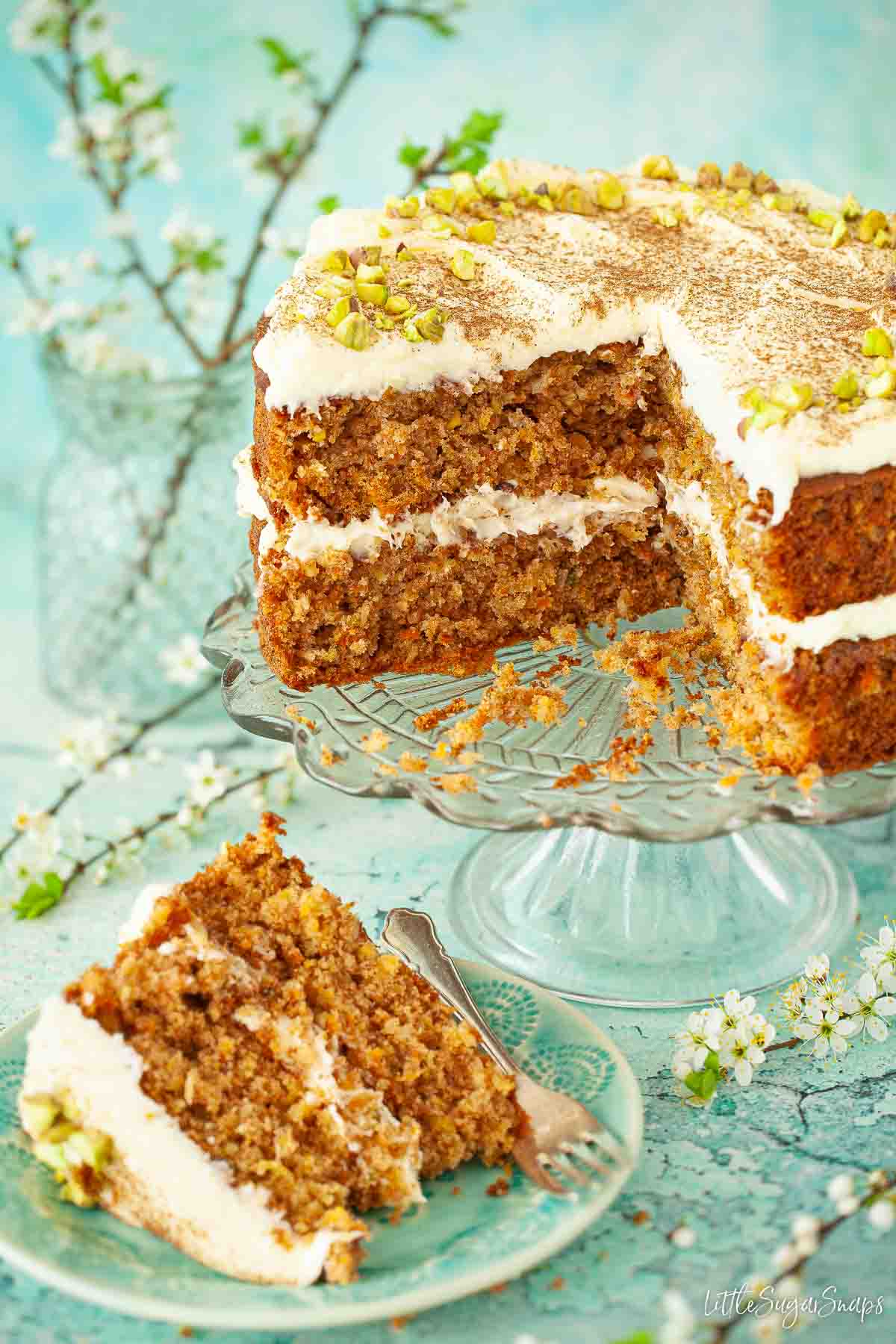 A cut into carrot, pineapple and coconut cake with a slice on a plate.