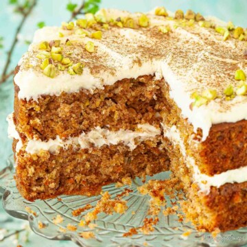 Cut into carrot and pineapple cake with cream cheese frosting and pistachio nuts.