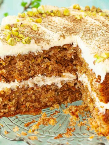 Cut into carrot and pineapple cake with cream cheese frosting and pistachio nuts.