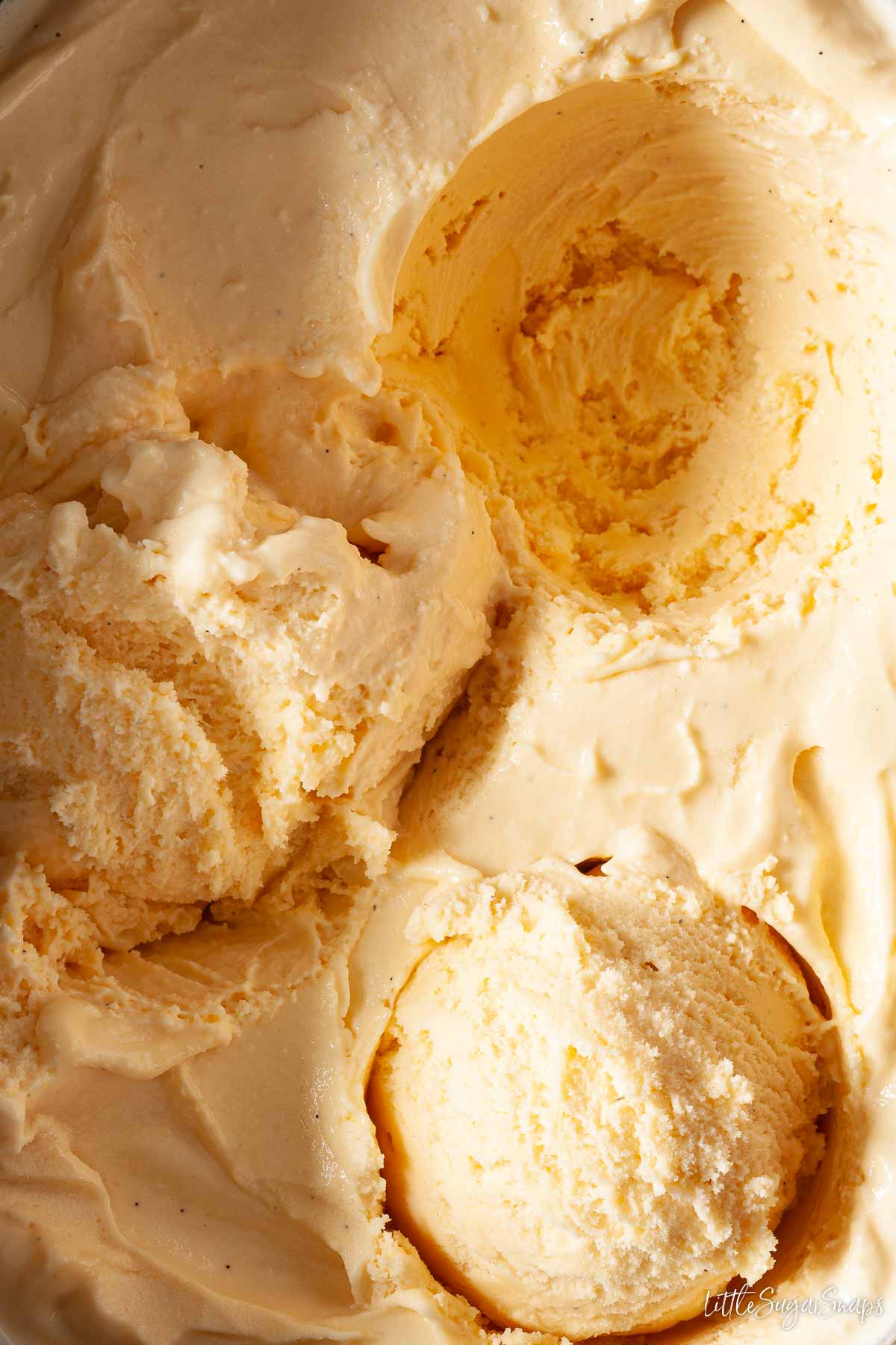 A batch of salted honey ice cream with scoops removed from it.