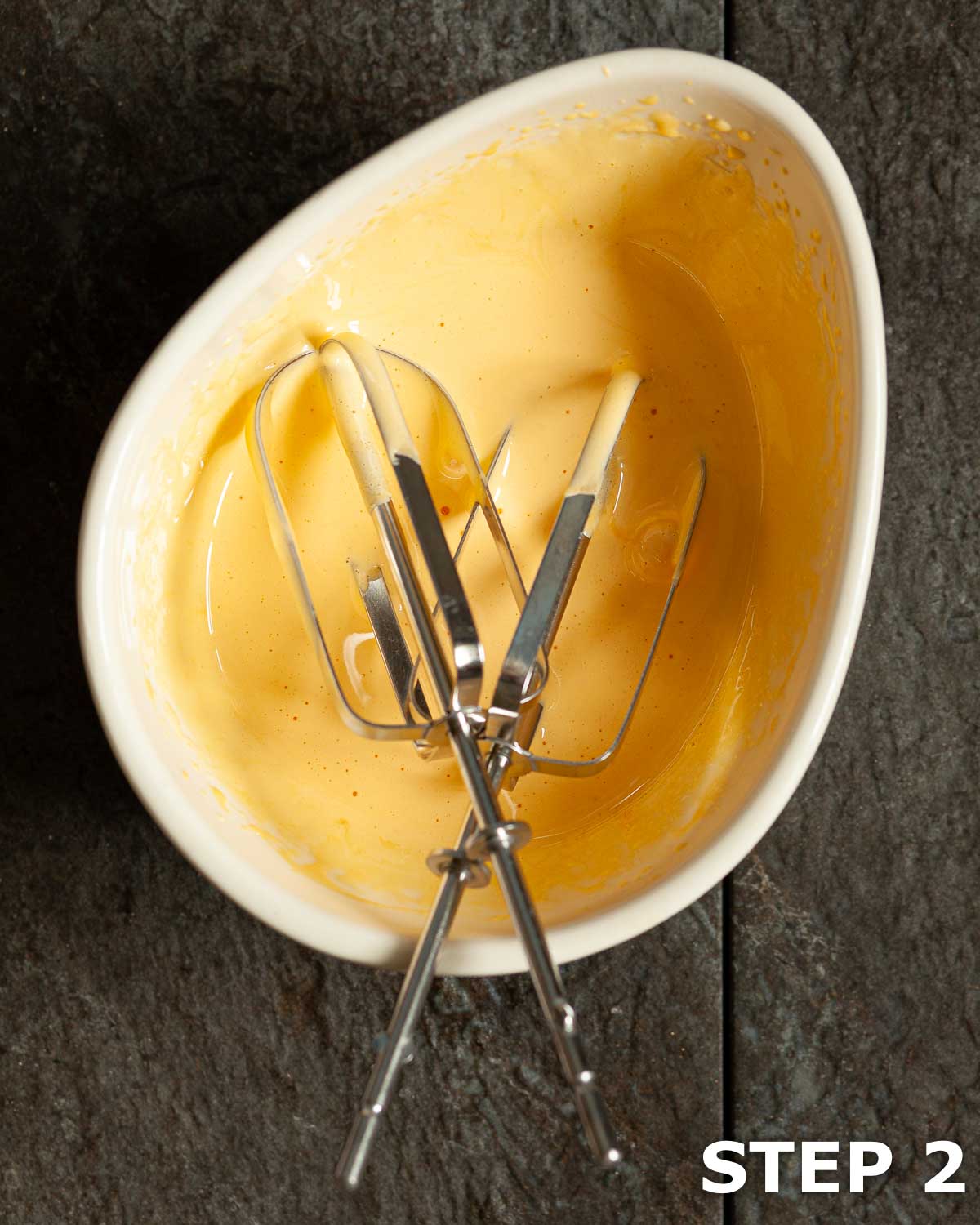 Egg yolks and sugar whisked in a bowl with beaters from an electric whisk.