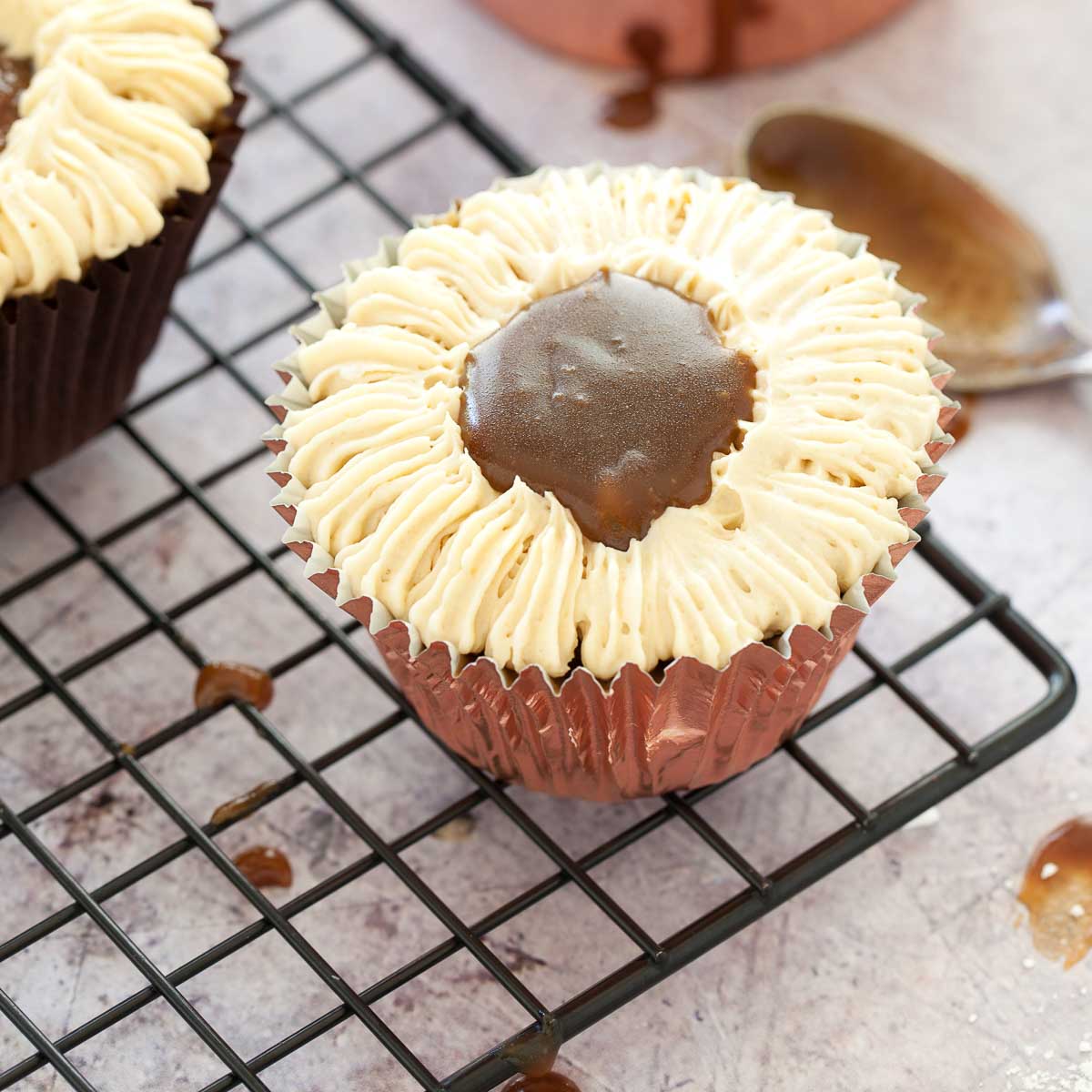 Decorating a sticky toffee cupcake with buttercream and toffee sauce.