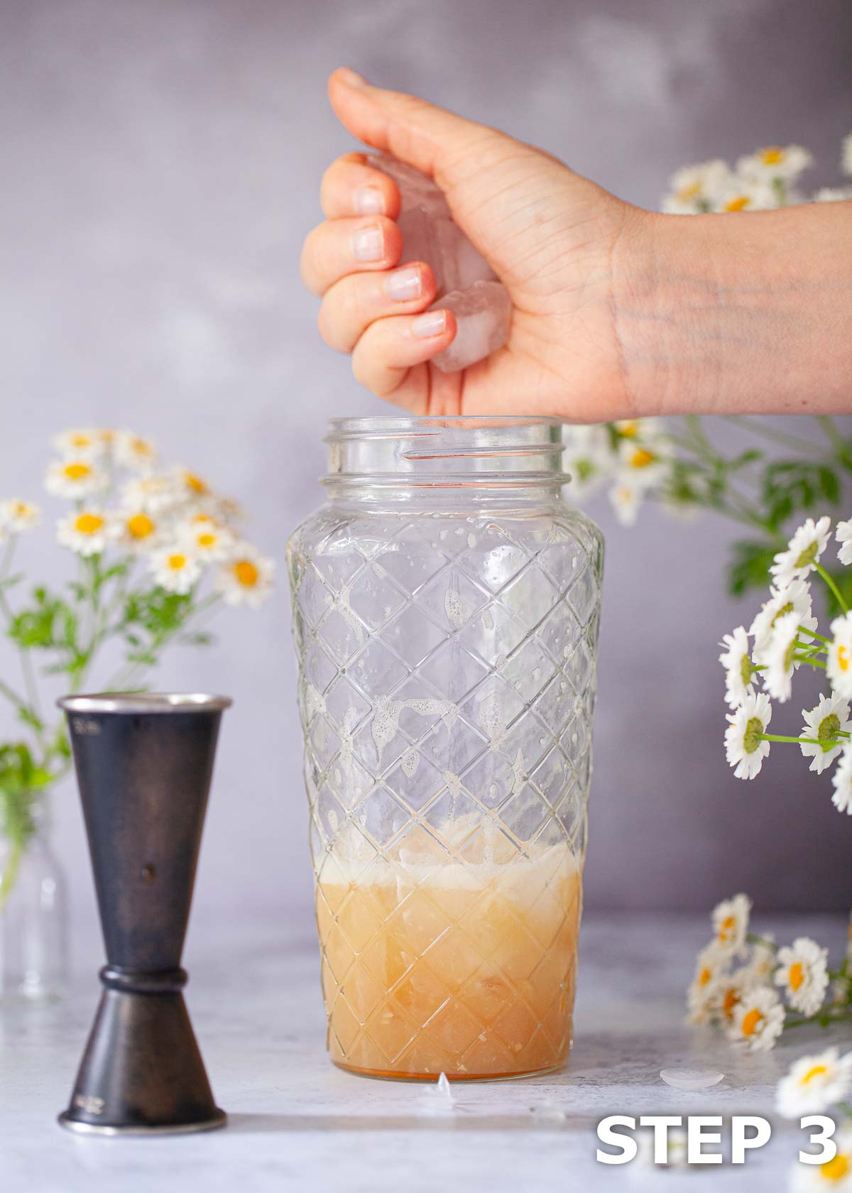 A person adding ice to a cocktail shaker after the dry shake.