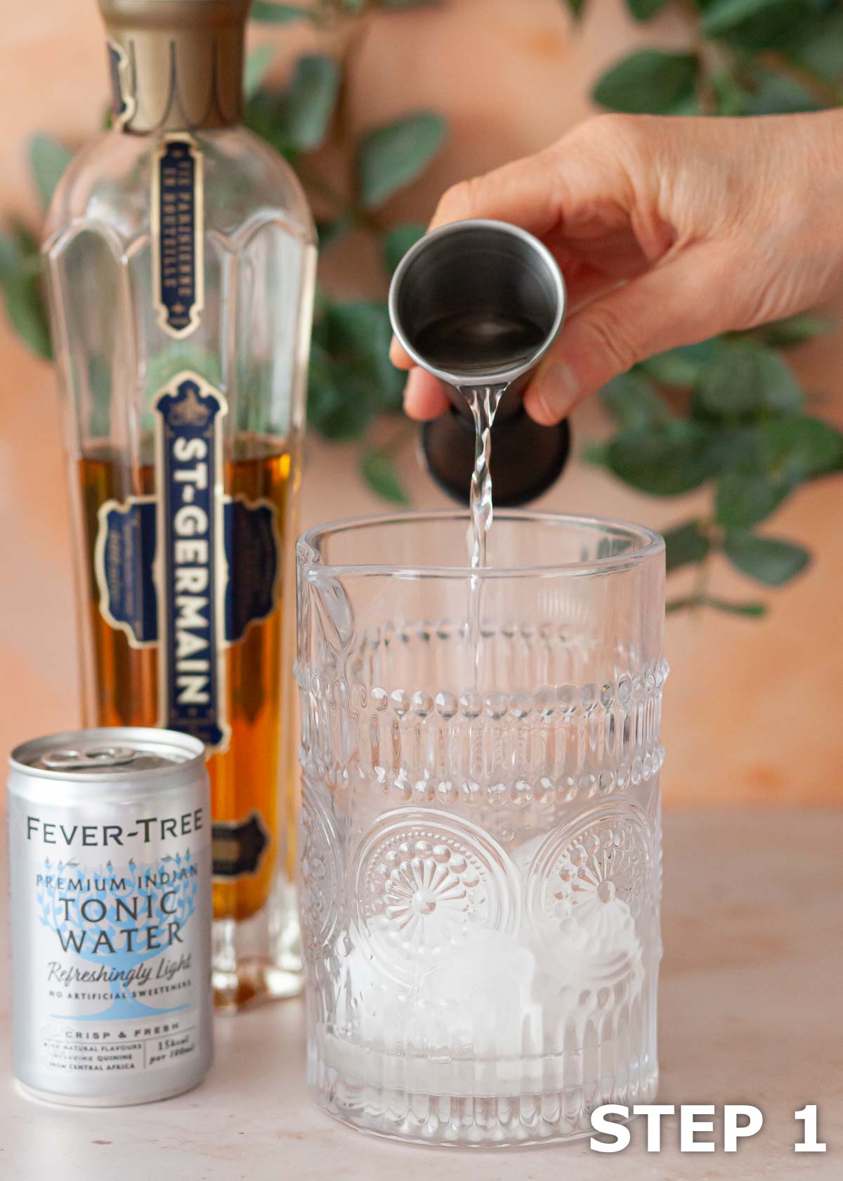 A person pouring gin into an ice filled bar jug.