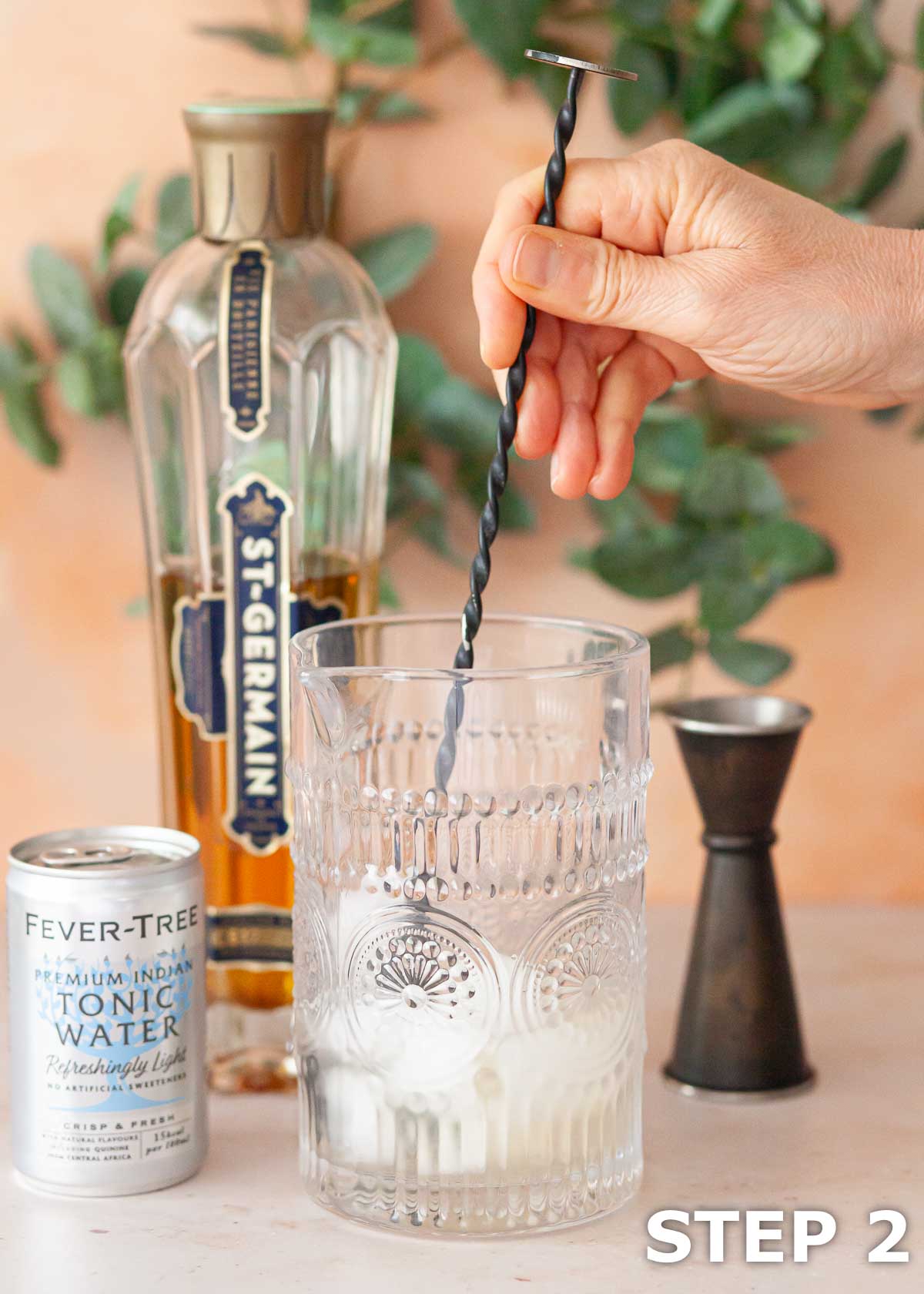 A person stirring alcohol with ice in a cocktail jug.