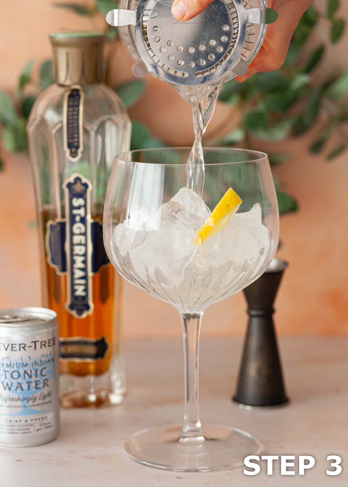 An alcoholic drink being poured into a Copa glass.