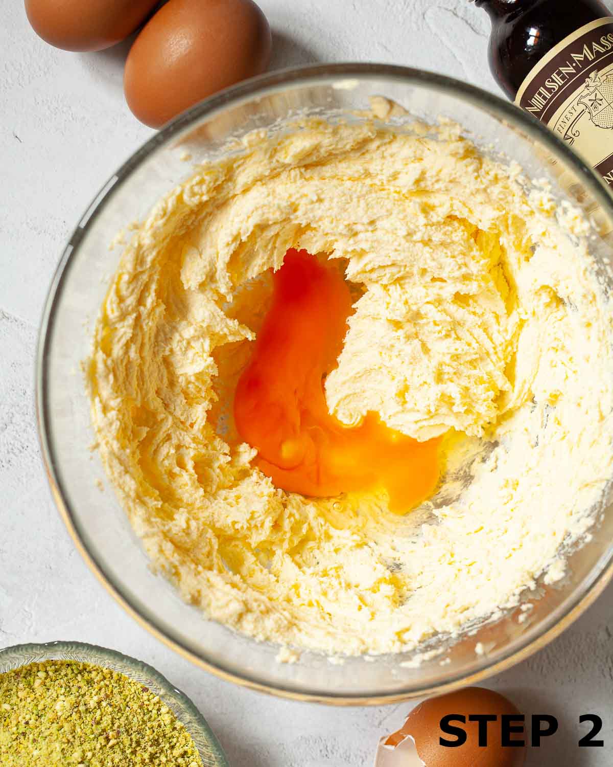 Creamed butter and sugar in a bowl with an egg cracked in ready to be mixed in.