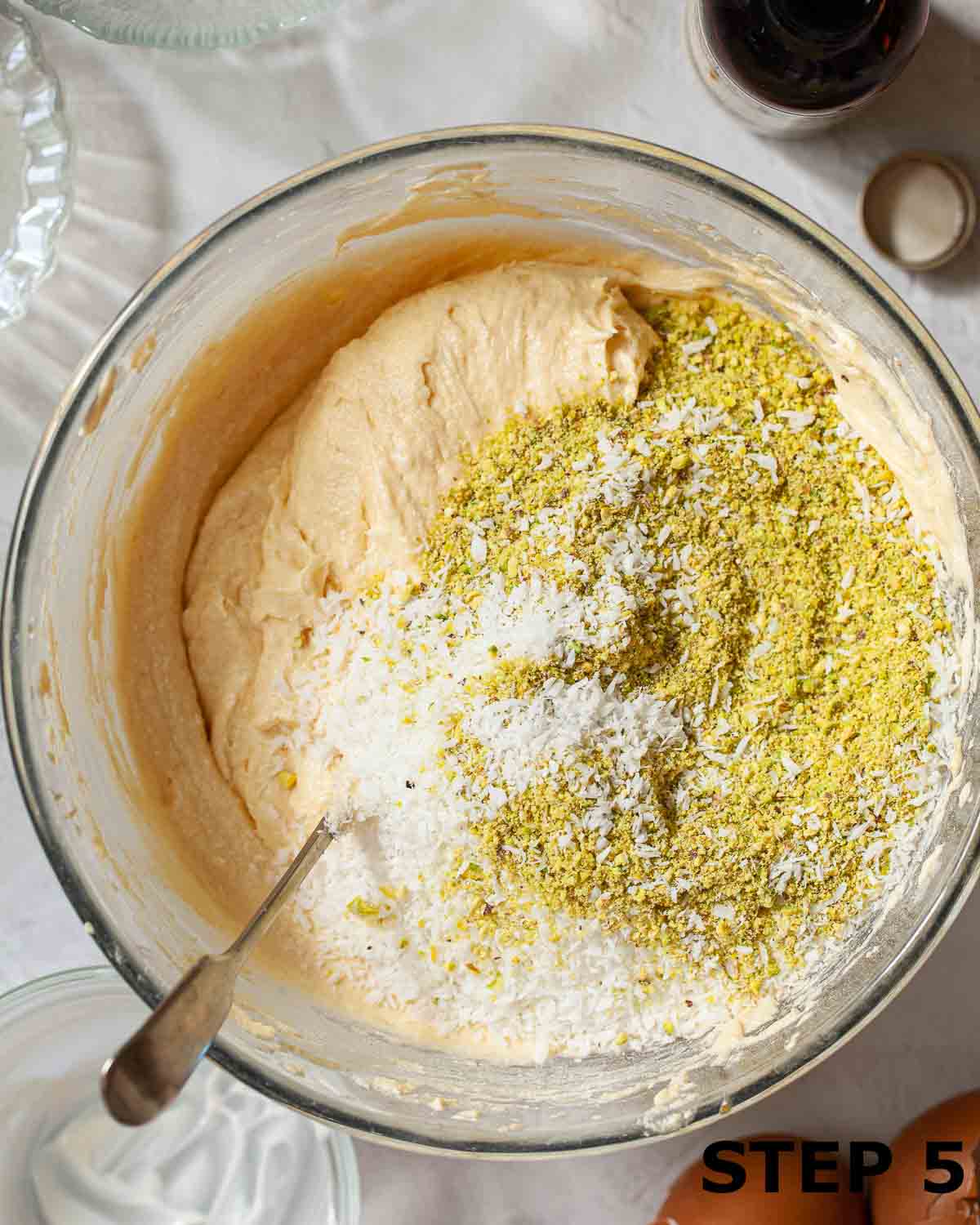 Desiccated coconut and ground pistachio nuts in a bowl with cake batter.