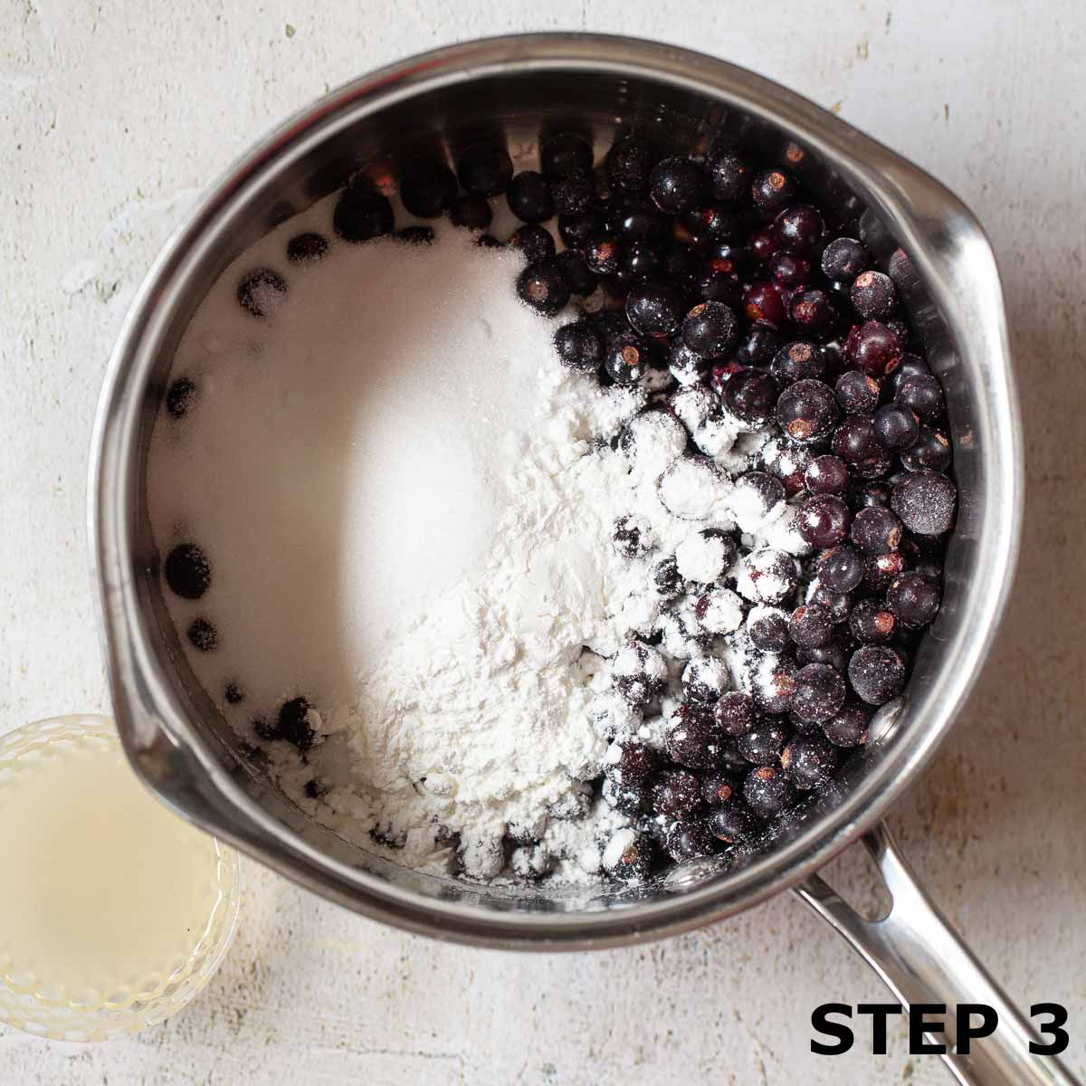Blackcurrants and sugar in a saucepan.